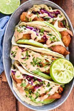 some tacos are sitting on a plate with lime wedges and cilantro