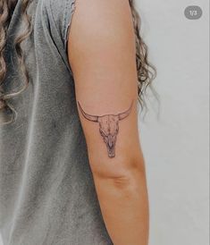 a woman's arm with a bull skull tattoo on the left side of her arm