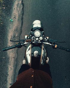 a person is riding a motorcycle down the street with their hand on the handlebars