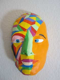 a paper mache head hanging on the wall in front of a white stucco wall