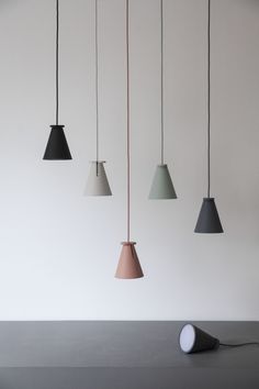 four different colored lamps hanging from the ceiling in a room with white walls and flooring