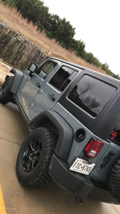 a gray jeep parked on the side of a road next to a parking space divider