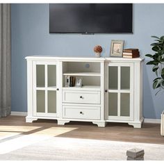 a white entertainment center with glass doors and drawers