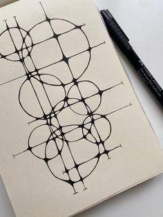 a notebook with an abstract design on it next to a pen and paper clipping