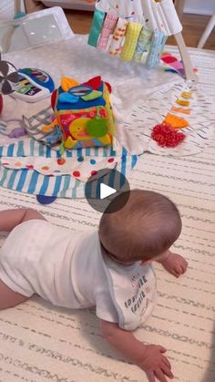 a baby laying on the floor next to a table with food and toys in it