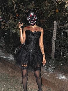 a woman wearing a mask and holding a baseball bat in her hand while standing outside at night