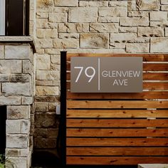 a wooden bench sitting in front of a stone building with a sign that reads 79 glennew ave