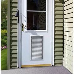 a white door sitting next to a window on the side of a green house with shutters