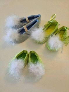 three pairs of baby shoes with fuzzy pom - poms on them