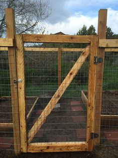 a wooden gate with wire around it in the middle of some dirt and grass area