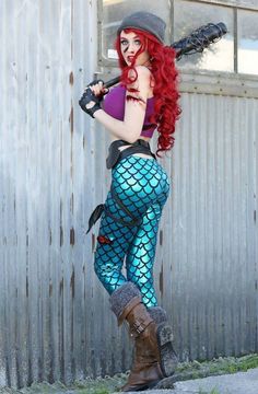 a woman with red hair is dressed up as a mermaid and holding a baseball bat