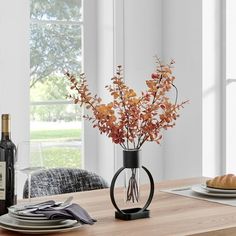 the table is set with wine, bread and flowers in a vase on top of it