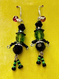 green and black beaded earrings sitting on top of a yellow table