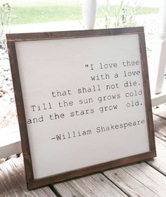 a wooden frame with a shakespeare quote on it sitting on a porch next to flowers