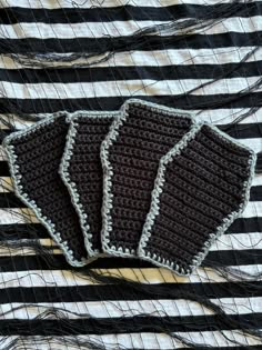 three crocheted coasters sitting on top of a striped cloth covered in black and white yarn