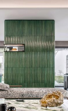 a room with a bed, coffee table and green curtained wall in the background