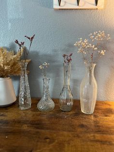 three vases on a table with flowers in them