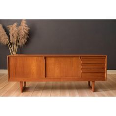 a wooden sideboard sitting on top of a hard wood floor next to a plant