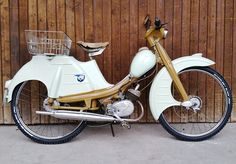 a white and gold motorcycle parked next to a wooden fence with a basket on the seat