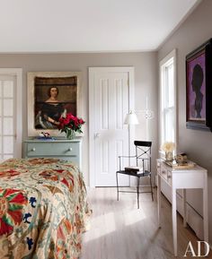 a bed room with a neatly made bed and a painting on the wall