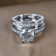 a close up of a diamond ring on top of a tan cloth surface with diamonds surrounding it