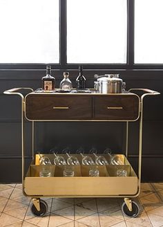 a kitchen cart with glasses on it in front of a window