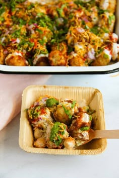 a casserole dish with meat and vegetables in it next to a tray of food