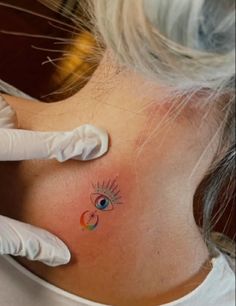 a woman's neck with an eye tattoo on her left side behind the ear