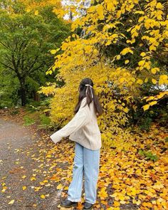 a woman standing in front of a tree with yellow leaves