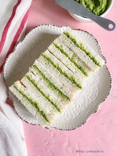 a white plate topped with a cut in half sandwich next to a bowl of guacamole