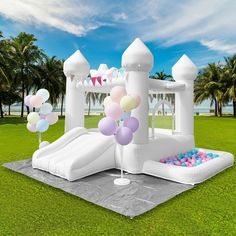 an inflatable bouncer with balloons and confetti is on the grass