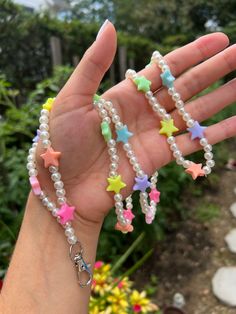 a person holding out their hand with some beads and stars on the beaded bracelets