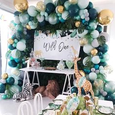 a jungle themed birthday party with balloons and decorations on the wall, including giraffes