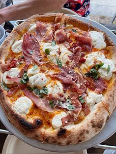 a pizza sitting on top of a pan covered in cheese and toppings with meat