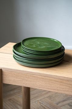 stack of green plates sitting on top of a wooden table