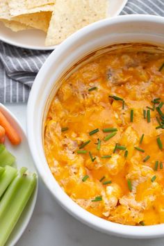 a white bowl filled with soup next to celery and carrots