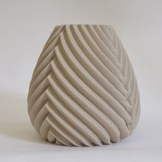 a large white vase sitting on top of a table next to a white wall and floor