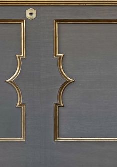 the door is painted gray with gold trimmings and has two square frames on each side