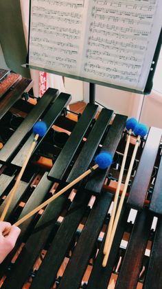 someone is playing musical instruments in front of an open sheet music stand with blue mallets