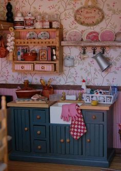 a dollhouse kitchen with pink and blue decor on the walls, wooden cabinets and shelves