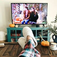 a person laying on the floor in front of a tv with their feet propped up