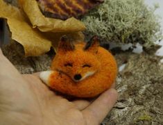 a hand holding a small stuffed animal that looks like a fox with it's mouth open