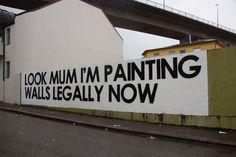 a large white building with black lettering on it's side and a bridge in the background