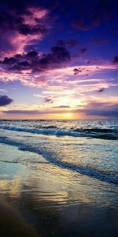 the sun is setting over the ocean with purple clouds