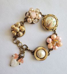 This beautiful bracelet has been made from 5 vintage earrings! The earrings are in light dusty peach, cream and gold. The bracelet is adjustable from 7 to 8 inches and has a mother of pearl  heart and peach glass bell flower charms.  The bracelet will arrive wrapped in tissue and in a silver gift bag.  It will be mailed USPS,  Ground Advantage with tracking and insurance,  in a small cardboard box. Antique Gold Bracelet, Jewelry Repurposed, Dusty Peach, Vintage Jewelry Repurposed, Vintage Clip Earrings, Peach Cream, Pearl Heart, Repurposed Jewelry, Silver Gifts