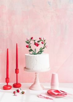 a white cake sitting on top of a table next to red candles