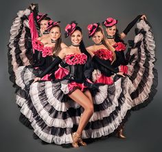 a group of women in black and white dresses with pink flowers on their heads posing for a photo