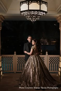 a man and woman standing in front of a chandelier