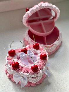 a pink and white cake with cherries on it sitting in a box next to another piece of cake