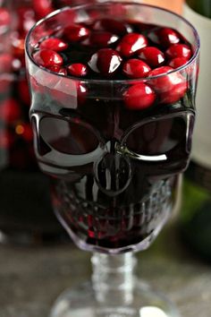 a wine glass filled with red cherries in the shape of a human skull head